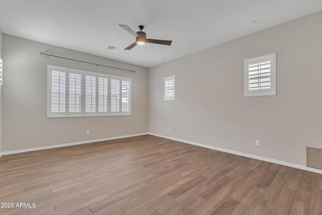 unfurnished room featuring ceiling fan, wood finished floors, visible vents, and baseboards