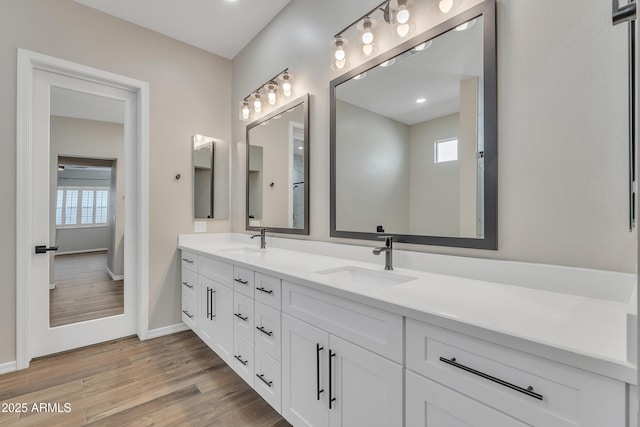 bathroom with double vanity, a sink, baseboards, and wood finished floors