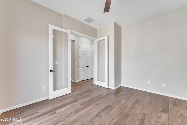 unfurnished bedroom with visible vents, baseboards, and wood finished floors