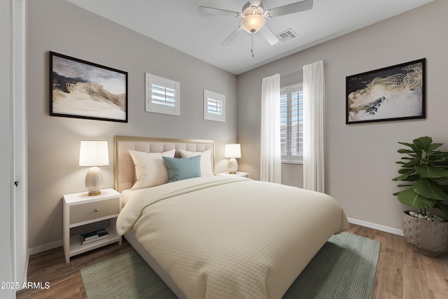 bedroom featuring a ceiling fan, baseboards, visible vents, and wood finished floors