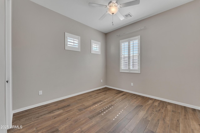 empty room featuring ceiling fan, wood finished floors, visible vents, and baseboards