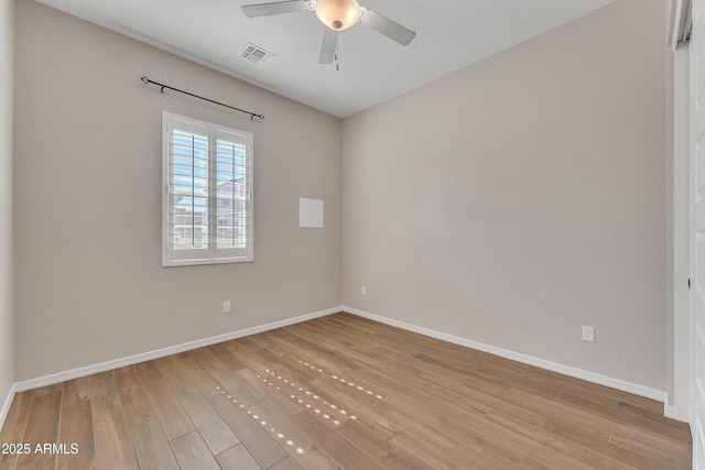 spare room featuring light wood-style floors, visible vents, baseboards, and a ceiling fan