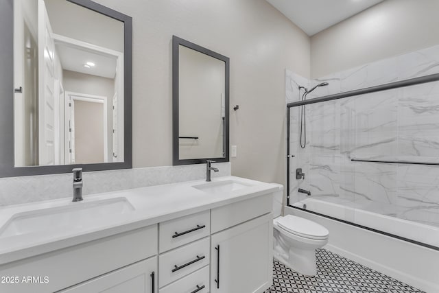 full bathroom featuring toilet, double vanity, combined bath / shower with glass door, and a sink