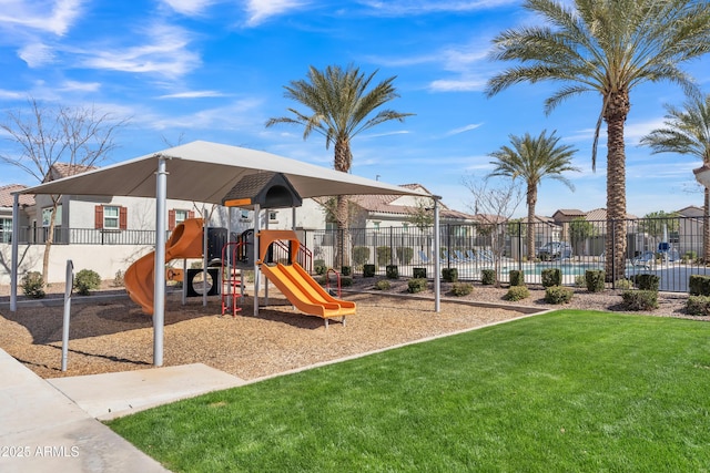 communal playground featuring a yard and fence