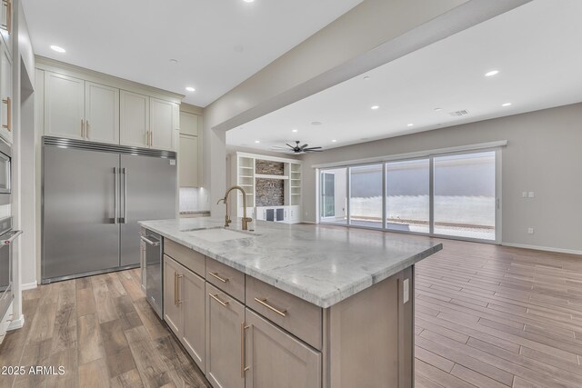 kitchen featuring an island with sink, light wood finished floors, appliances with stainless steel finishes, and a sink