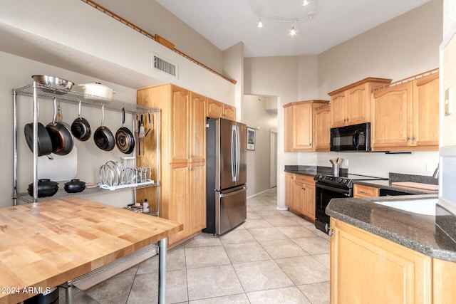 kitchen with black appliances, wood counters, light tile patterned floors, and kitchen peninsula