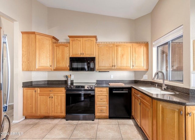 kitchen with lofted ceiling, black appliances, sink, dark stone countertops, and light tile patterned flooring