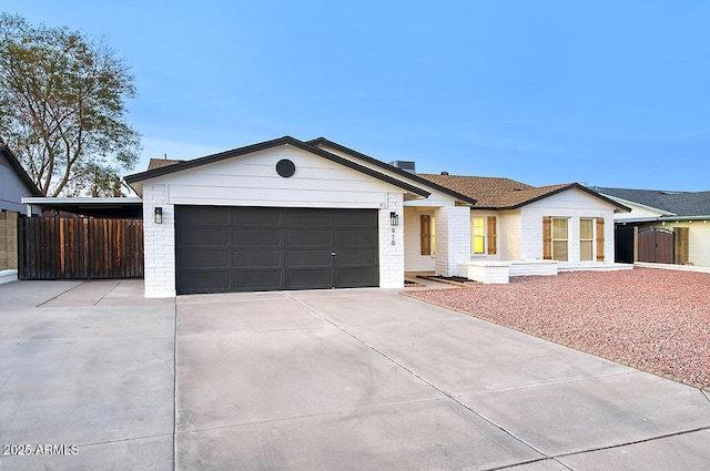 single story home with concrete driveway, brick siding, fence, and an attached garage