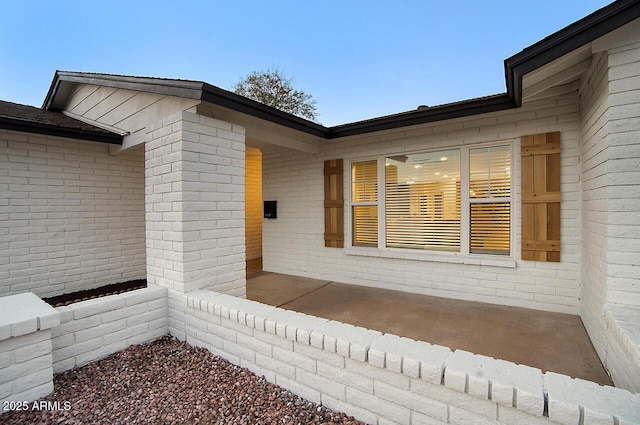 property entrance with a patio and brick siding