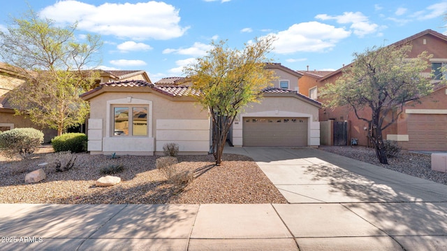 mediterranean / spanish home featuring concrete driveway, an attached garage, a tile roof, and stucco siding