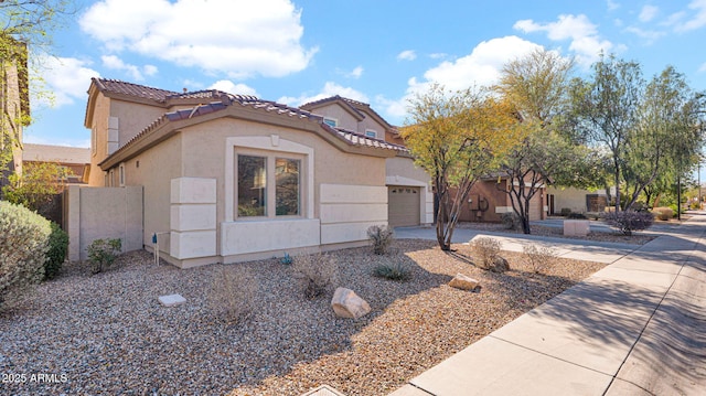 mediterranean / spanish home featuring driveway, an attached garage, a tile roof, and stucco siding