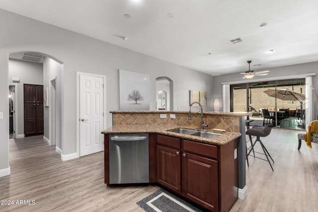 kitchen with backsplash, stainless steel dishwasher, ceiling fan, a kitchen island with sink, and sink