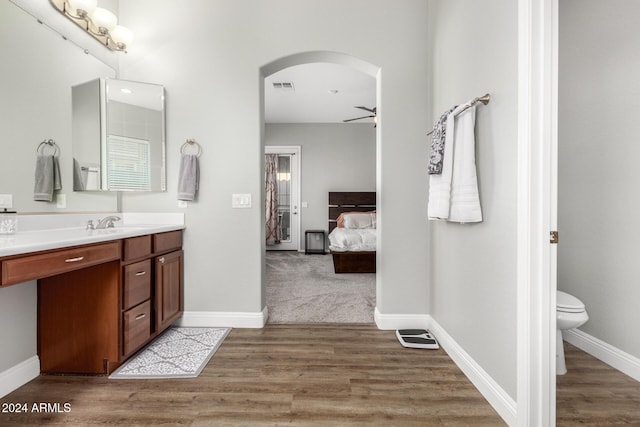 bathroom with wood-type flooring, vanity, toilet, and ceiling fan