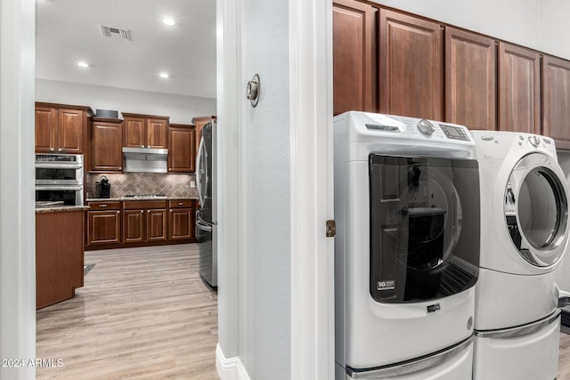 laundry area featuring light wood-type flooring and separate washer and dryer