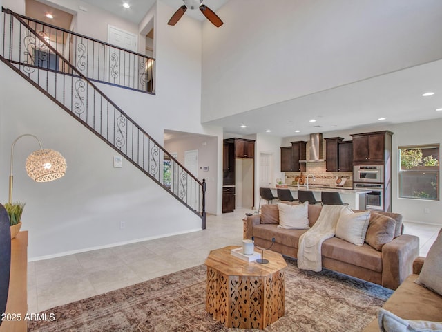 tiled living room featuring ceiling fan, sink, and a high ceiling