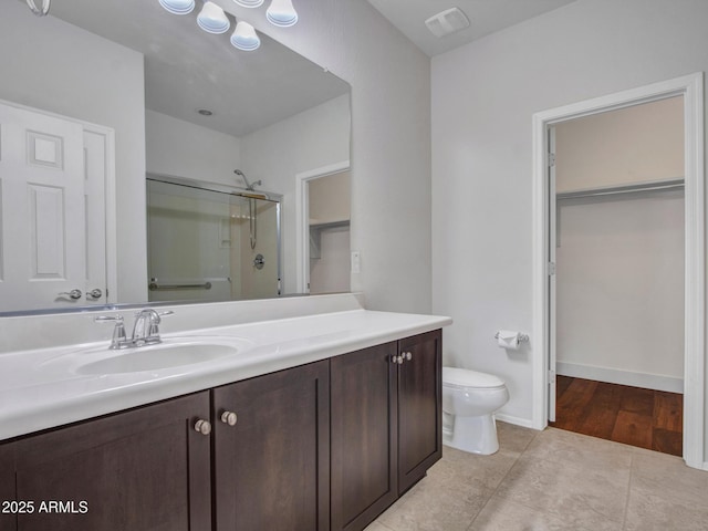 bathroom featuring tile patterned floors, toilet, a shower with shower door, and vanity