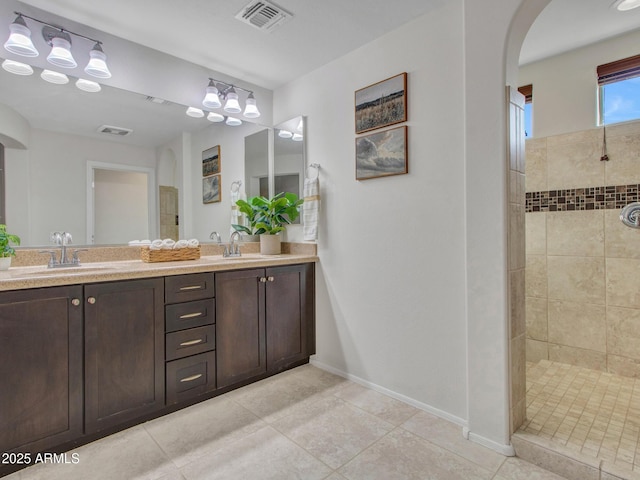 bathroom with tile patterned flooring, vanity, and tiled shower