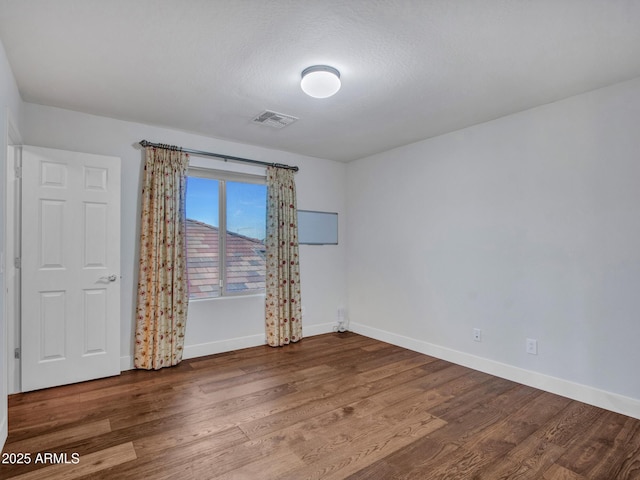 unfurnished room with hardwood / wood-style floors and a textured ceiling