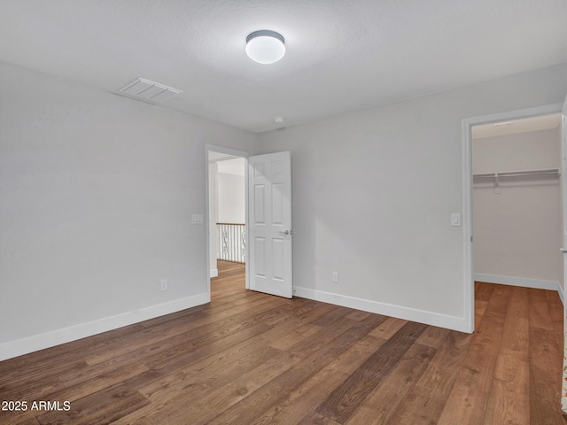 unfurnished bedroom featuring hardwood / wood-style floors, a spacious closet, and a closet