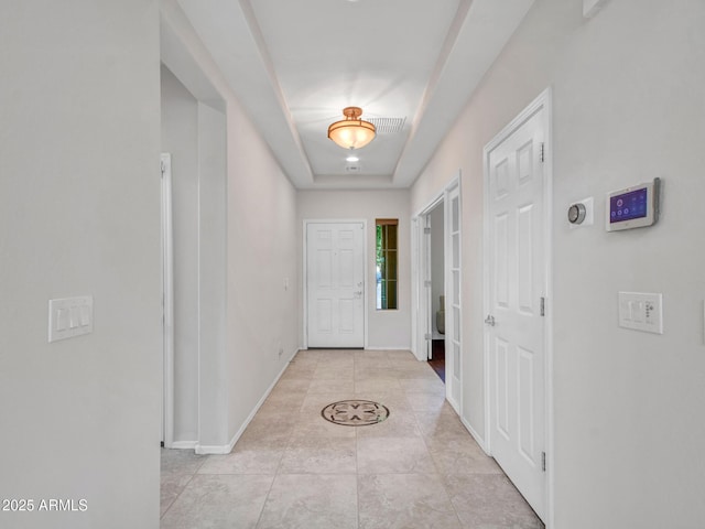 doorway to outside featuring light tile patterned flooring and a raised ceiling