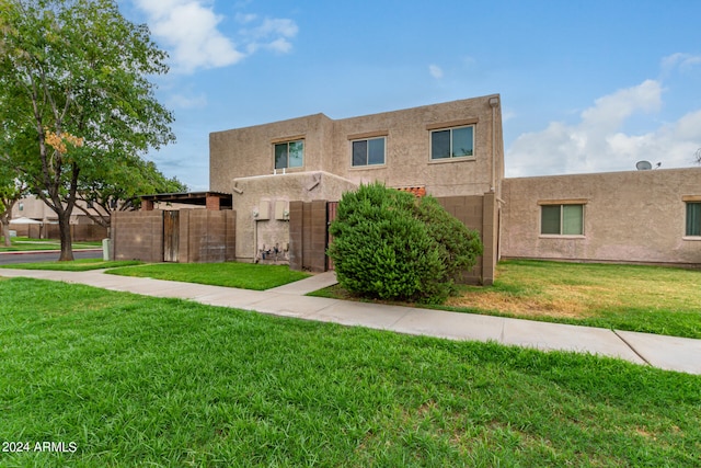 pueblo-style home featuring a front lawn