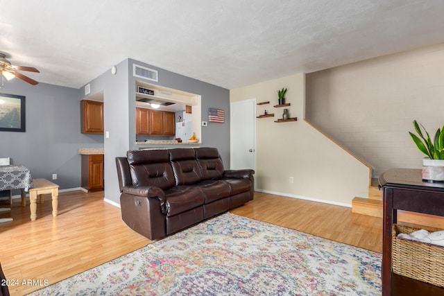 living room featuring a textured ceiling, light hardwood / wood-style flooring, and ceiling fan