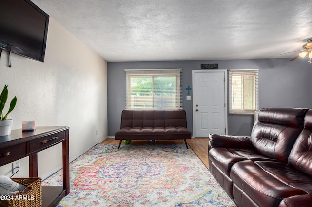 living room featuring a textured ceiling, hardwood / wood-style floors, and ceiling fan