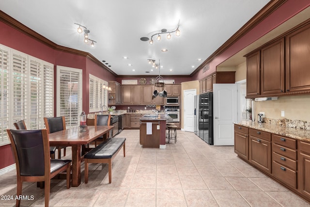 kitchen with light stone counters, a kitchen island, light tile patterned floors, stainless steel appliances, and crown molding