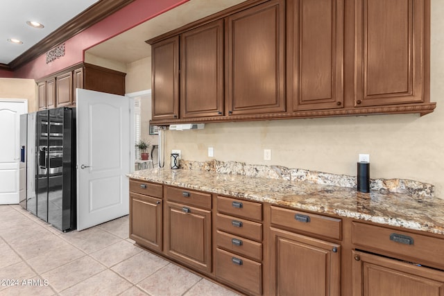 kitchen with black refrigerator with ice dispenser, light stone counters, light tile patterned floors, and crown molding