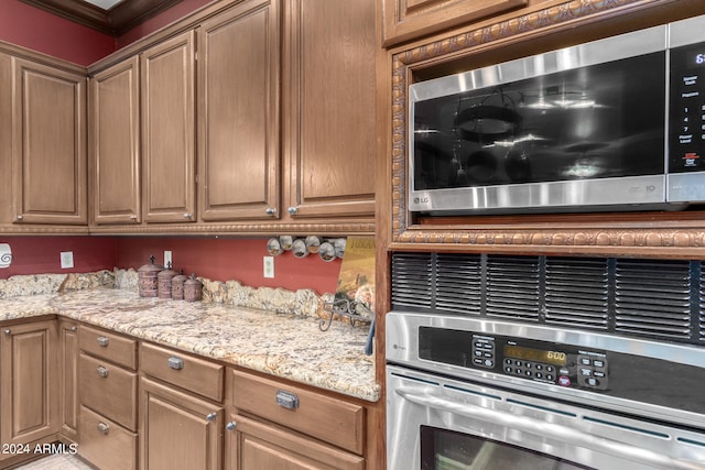 kitchen with light stone countertops, appliances with stainless steel finishes, and ornamental molding