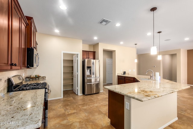 kitchen featuring a kitchen island with sink, stainless steel appliances, sink, light stone countertops, and pendant lighting