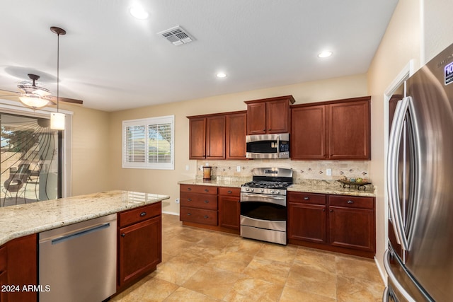 kitchen with tasteful backsplash, ceiling fan, stainless steel appliances, pendant lighting, and light stone counters