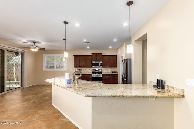 kitchen with appliances with stainless steel finishes, sink, kitchen peninsula, pendant lighting, and light stone counters