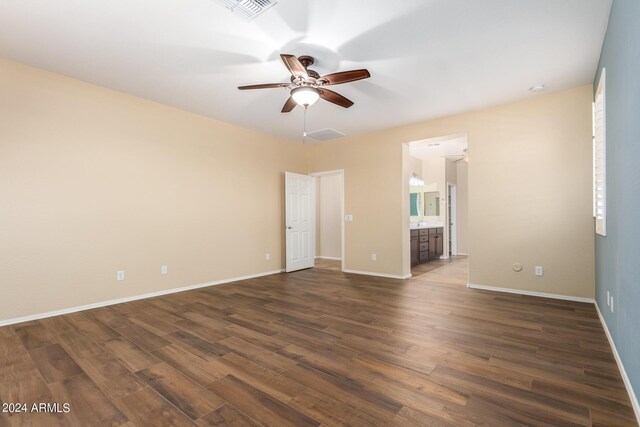 spare room featuring dark wood-type flooring, baseboards, visible vents, and a ceiling fan