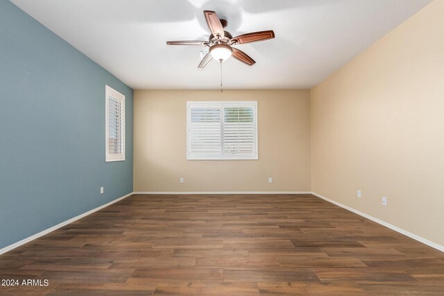 spare room featuring baseboards, dark wood-type flooring, and a ceiling fan