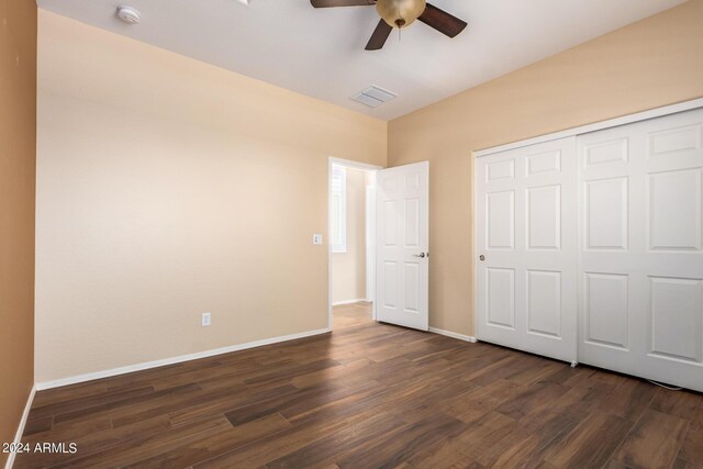 unfurnished bedroom with a closet, visible vents, baseboards, a ceiling fan, and dark wood-style floors
