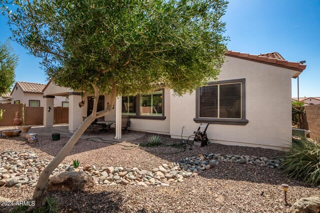 view of front of home with a patio area, fence, stucco siding, and a tiled roof