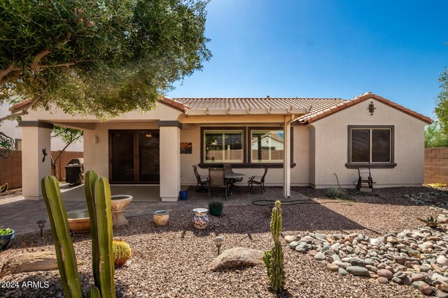 back of house with a tiled roof, stucco siding, fence, and a patio