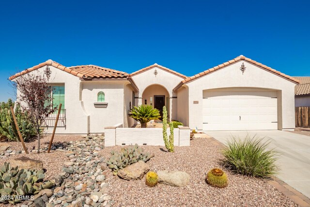 mediterranean / spanish-style house featuring a tiled roof, a garage, concrete driveway, and stucco siding