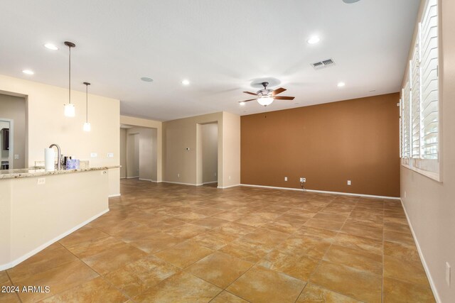 unfurnished living room featuring a sink, a ceiling fan, baseboards, visible vents, and recessed lighting