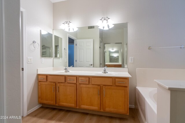 bathroom featuring wood-type flooring, vanity, and a bath