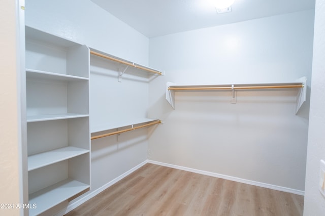 walk in closet with light hardwood / wood-style floors