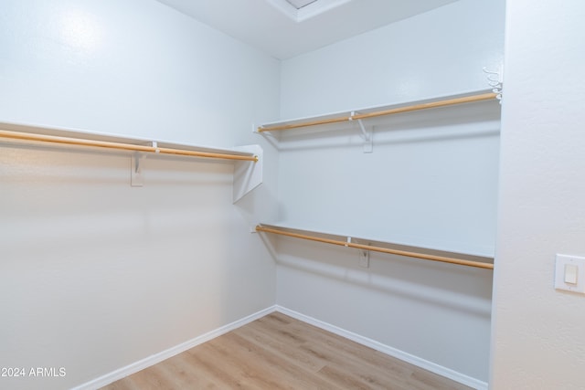 walk in closet with light hardwood / wood-style flooring