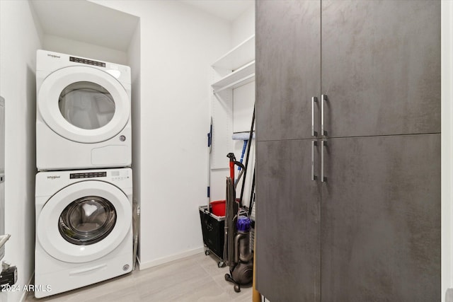 laundry room featuring cabinets, stacked washer / dryer, and light tile patterned floors