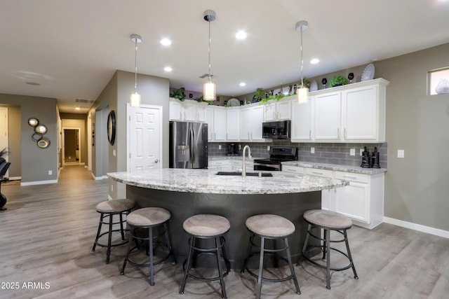 kitchen featuring sink, white cabinetry, tasteful backsplash, appliances with stainless steel finishes, and an island with sink