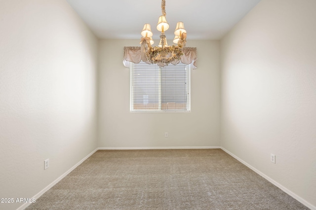 carpeted empty room featuring an inviting chandelier and baseboards