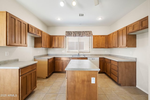 kitchen featuring visible vents, brown cabinets, a sink, a center island, and white dishwasher