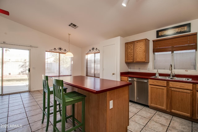 kitchen featuring lofted ceiling, a kitchen bar, sink, a center island, and stainless steel dishwasher