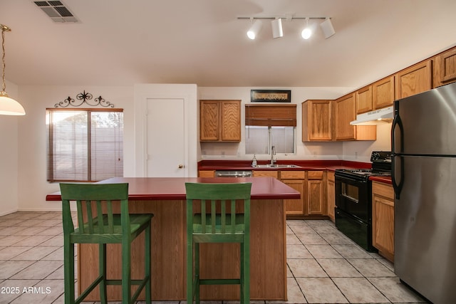 kitchen featuring a kitchen island, decorative light fixtures, sink, a kitchen bar, and stainless steel appliances