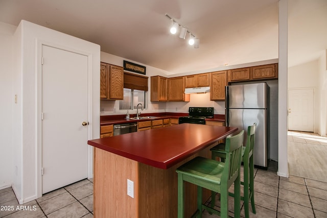 kitchen with sink, a kitchen bar, a center island, light tile patterned floors, and stainless steel appliances